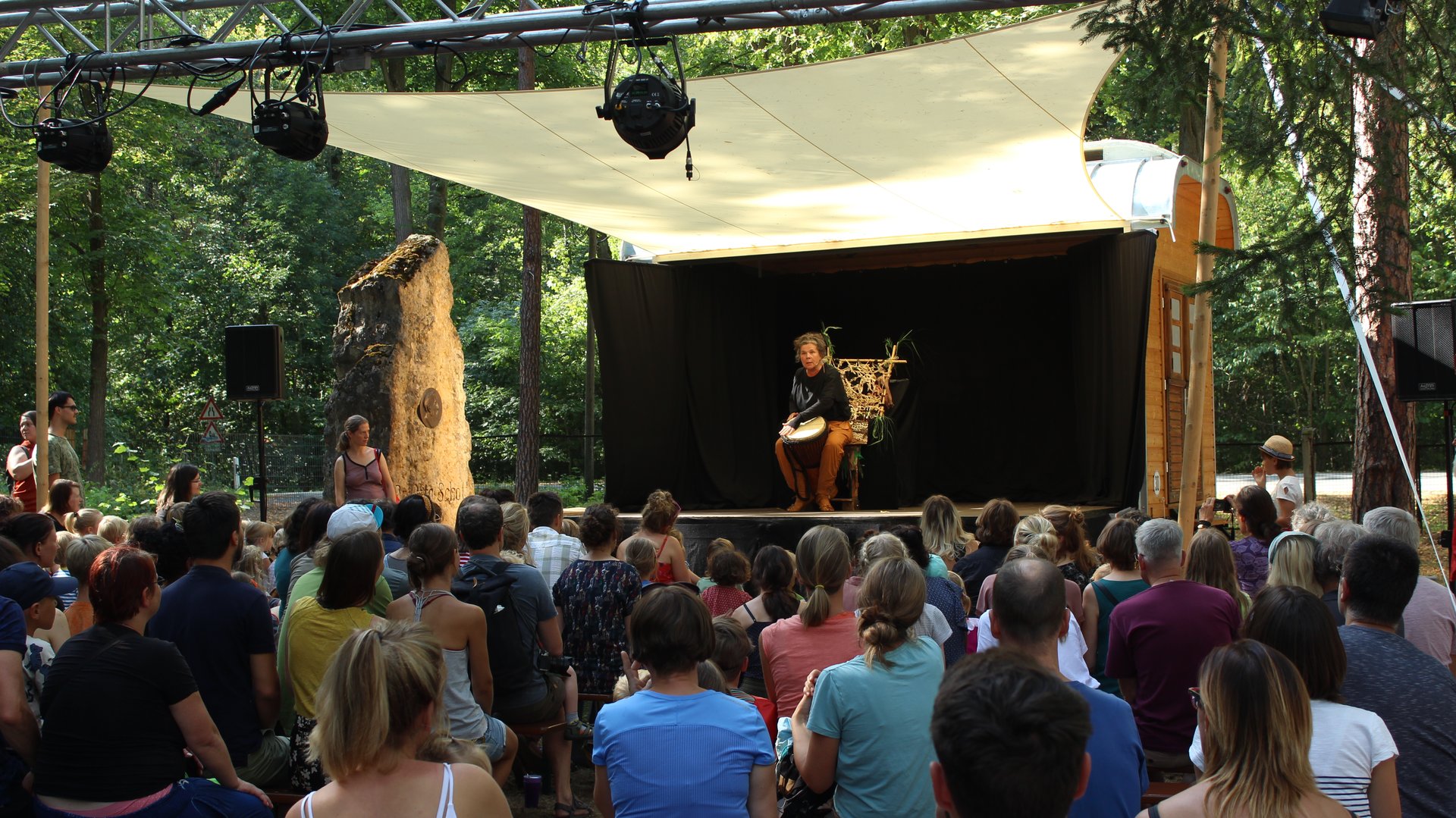 Viele Menschen vor dem Wagen, eine Schauspielerin auf der Bühne